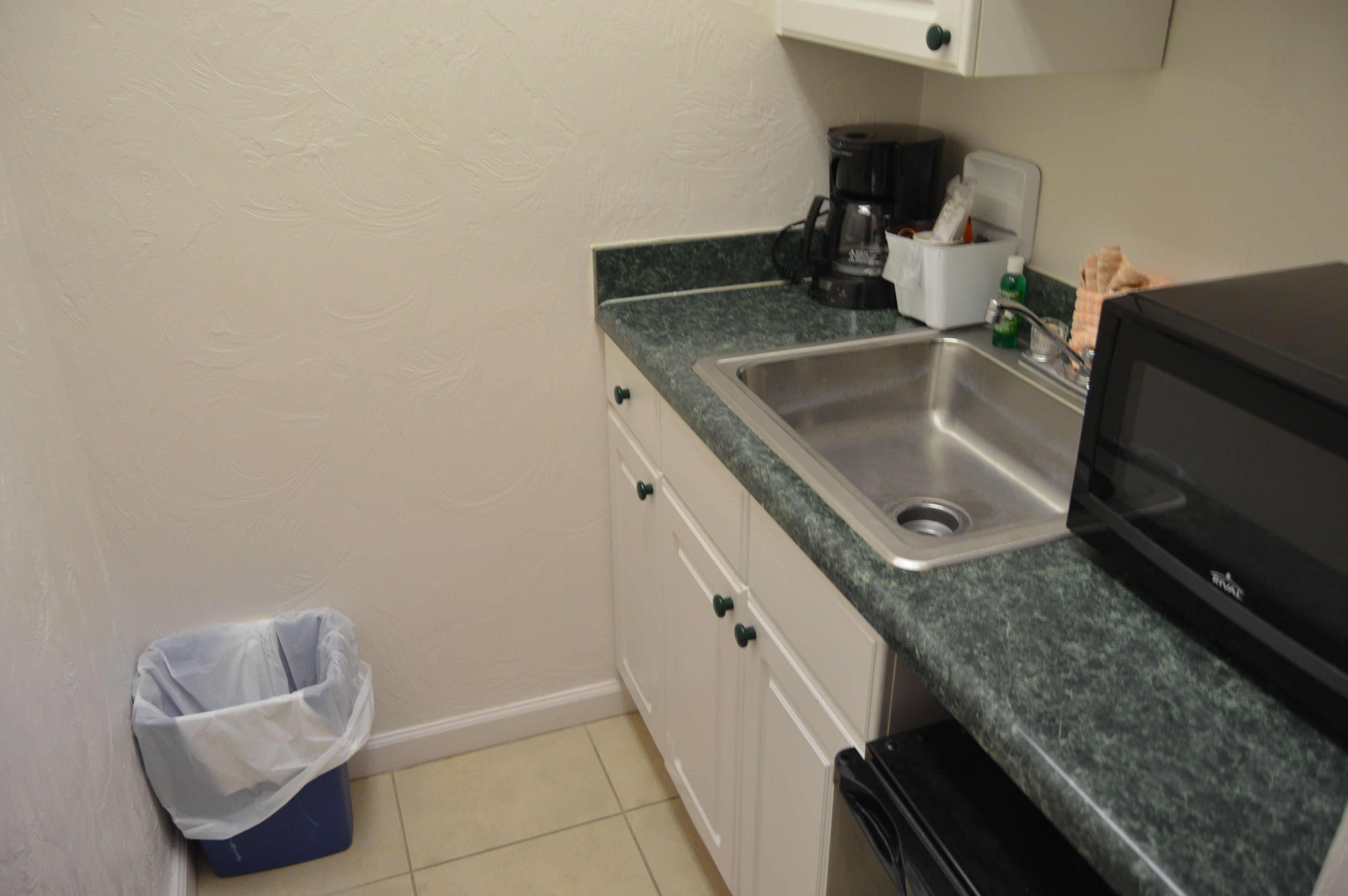 Una cocina pequeña con un lavabo, un microondas y una cafetera.