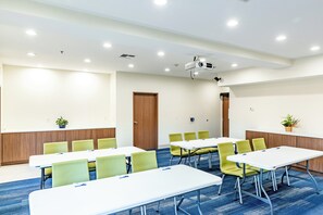 A conference room with white tables, green chairs, a projector, and a blue carpet. - Holiday Inn Express Hereford by IHG (Hereford)