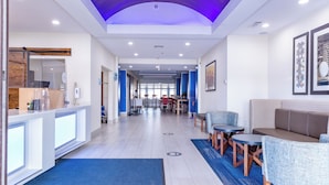 Un vestíbulo de hotel con mostrador de recepción, zona de estar y comedor.