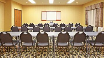 A conference room with a long table, multiple chairs, a bulletin board, and patterned carpet.