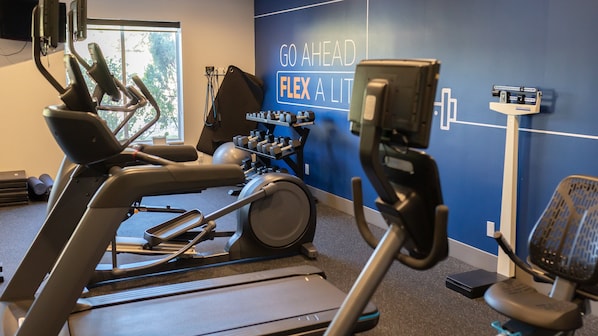 A gym with exercise equipment, a wall with motivational text, and a window with natural light.