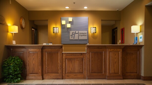 A reception area with a checkered floor, wooden reception desk, wall-mounted clock, and Holiday Inn Express signage. - Holiday Inn Express Hotel & Suites Mountain Home by IHG (Mountain Home)