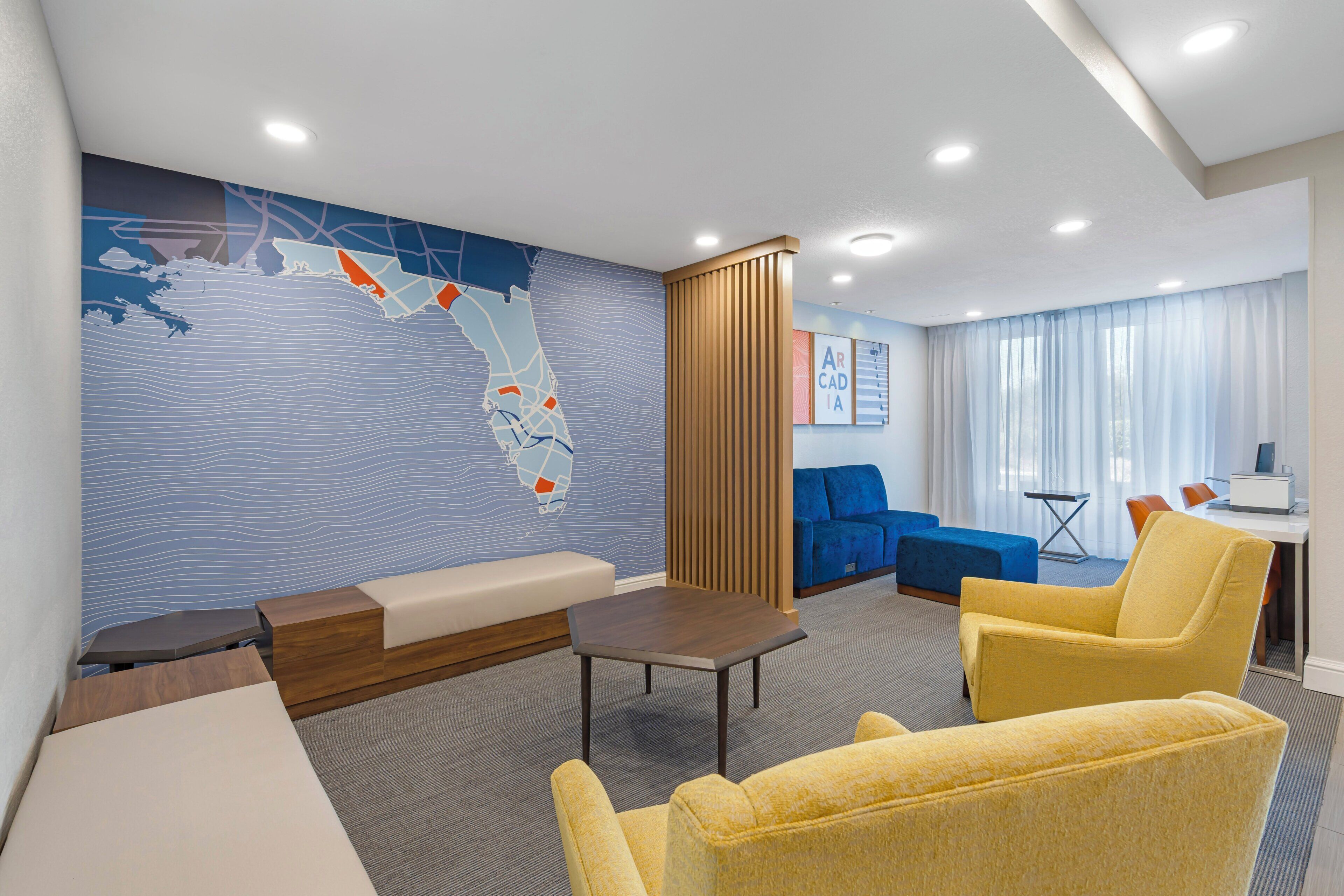 A hotel lobby with a large wall map, seating areas, and a desk with a computer.