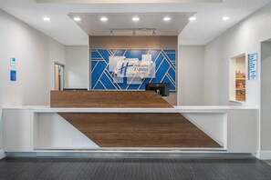 A hotel reception desk with a modern design, including a geometric patterned wall and a wooden reception counter.