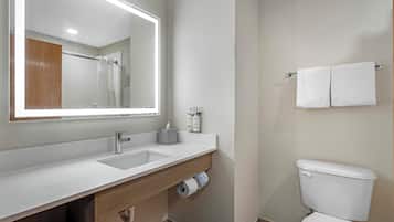 A modern bathroom with a large mirror, a sink, a toilet, and a shower area.