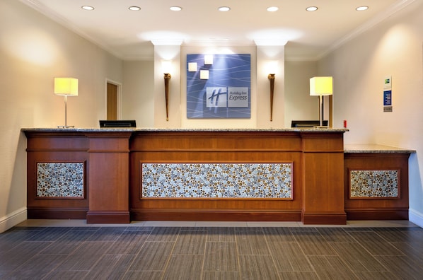 Una recepción con el letrero de Holiday Inn Express, dos lámparas fijadas a la pared y un reverso de azulejos estampados.