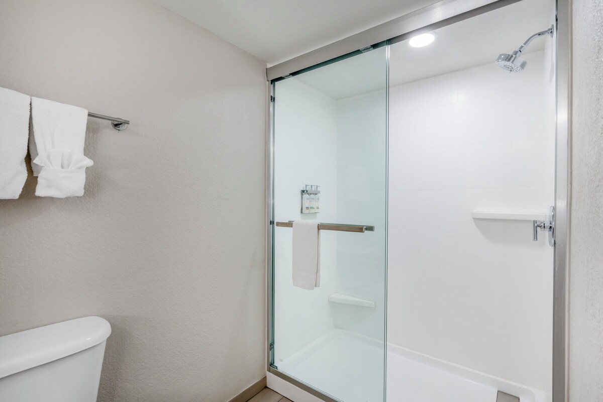A modern bathroom with a glass-enclosed shower, a toilet, and a towel rack.