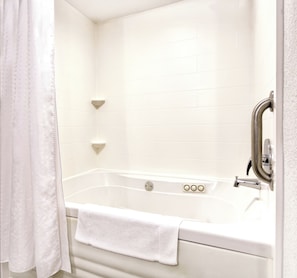 Un baño blanco con una bañera, un cortinón de ducha y una toalla.