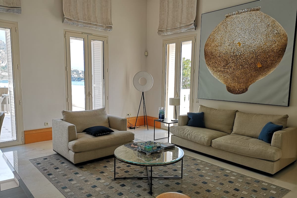 A living room with two beige sofas, a glass coffee table, a floor lamp, and a large abstract painting.