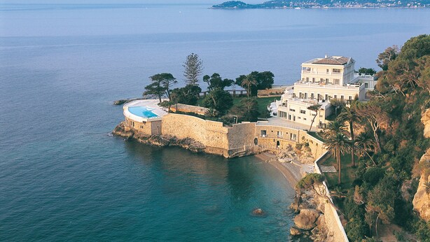 A coastal property with a large building, a swimming pool, and a stone wall overlooking the sea. - Hôtel Cap-Estel (Èze)