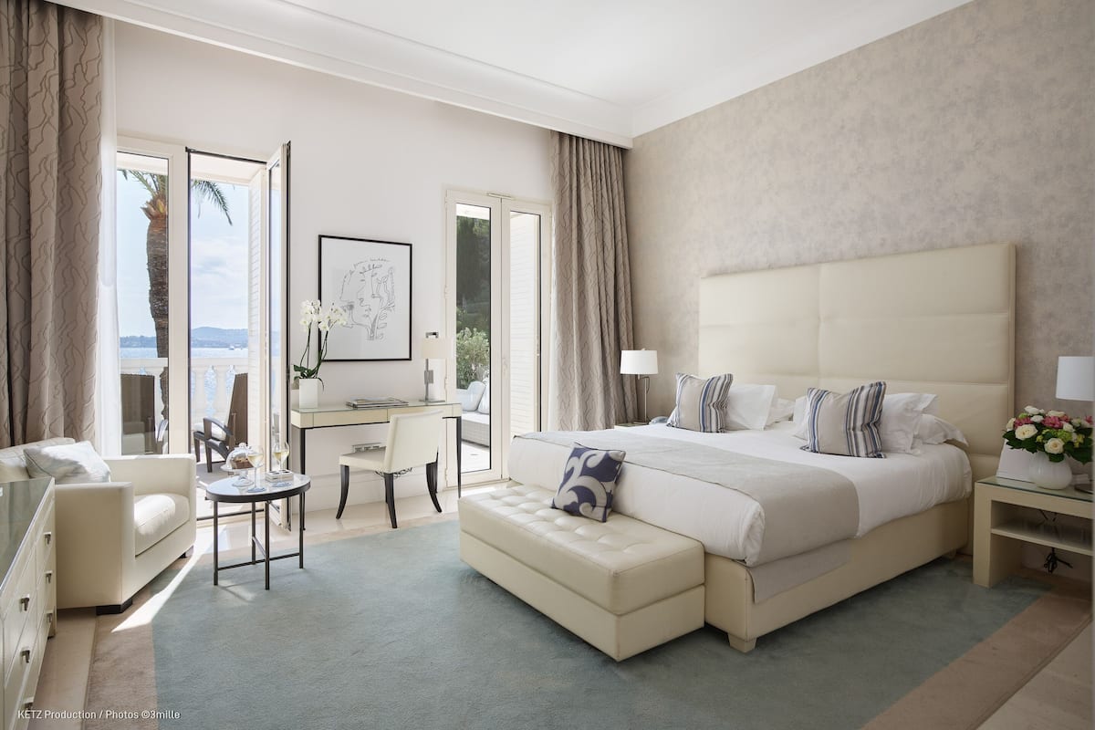 A spacious bedroom with a large bed, a desk, and a view of the outdoors.