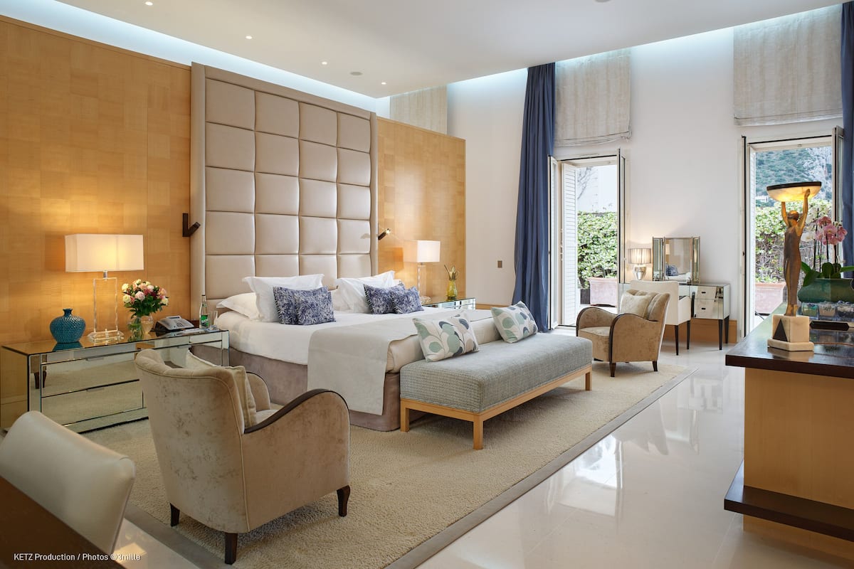A modern hotel bedroom with a large bed, a desk, and a seating area.