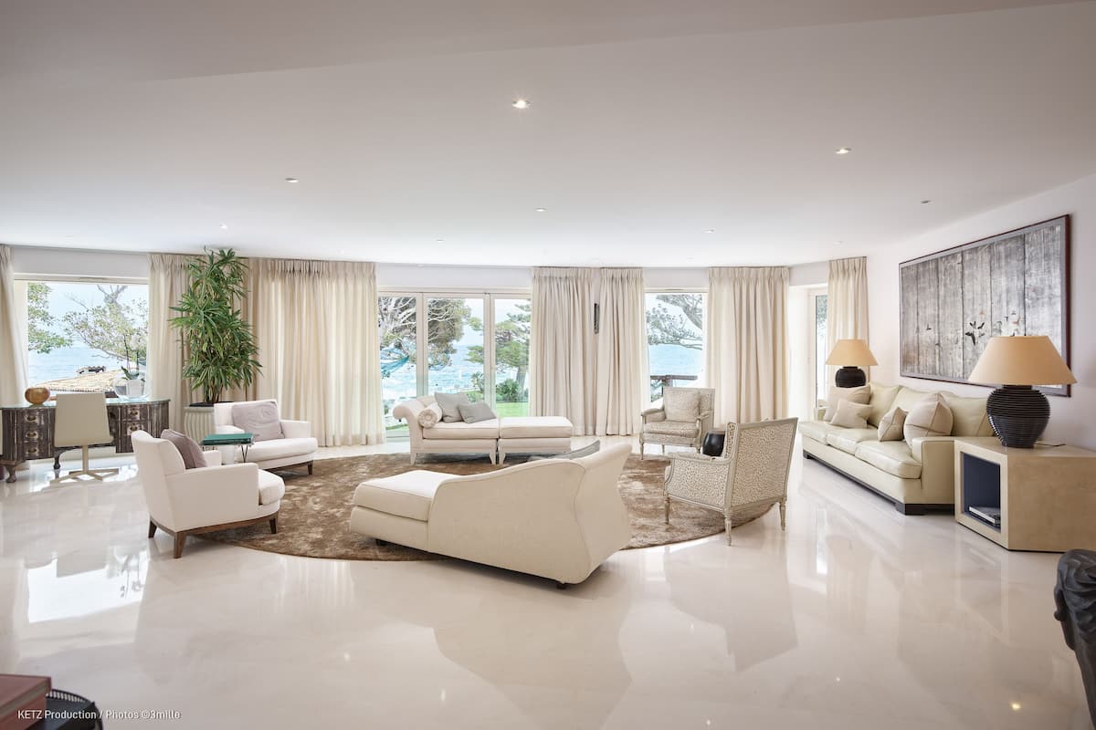 A spacious living room with a large window, a sofa, a coffee table, and a lamp.