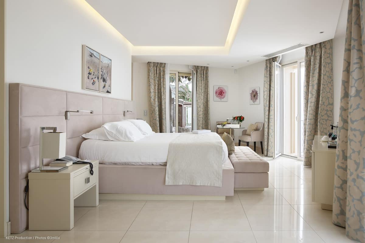 A modern bedroom with a large bed, bedside tables, a desk, and a bench.