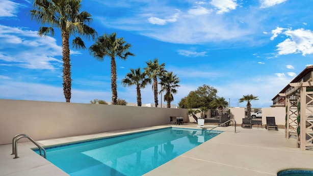 Una piscina rectangular con una escalera metálica en un lateral, rodeada por una terraza de tonos claros.