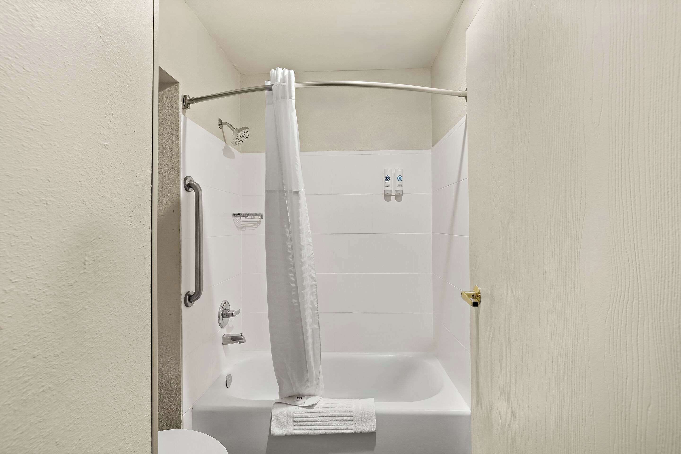 A bathroom with a shower, toilet, and a towel rack.