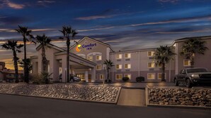 Un hotel Comfort Inn con un diseño moderno, que destaca un letrero llamativo, varios pisos y un área de estacionamiento con una camioneta Toyota.