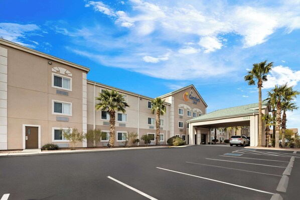 A hotel with a flat facade, palm trees, and a clear blue sky.