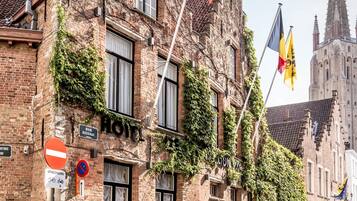 A historic building with ivy, a 'HOTEL' sign, and flags.
