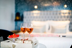 A bed with white linens and pillows, a bedside table with a glass of wine and strawberries, and a decorative box. - Hotel de Castillion (Bruges)