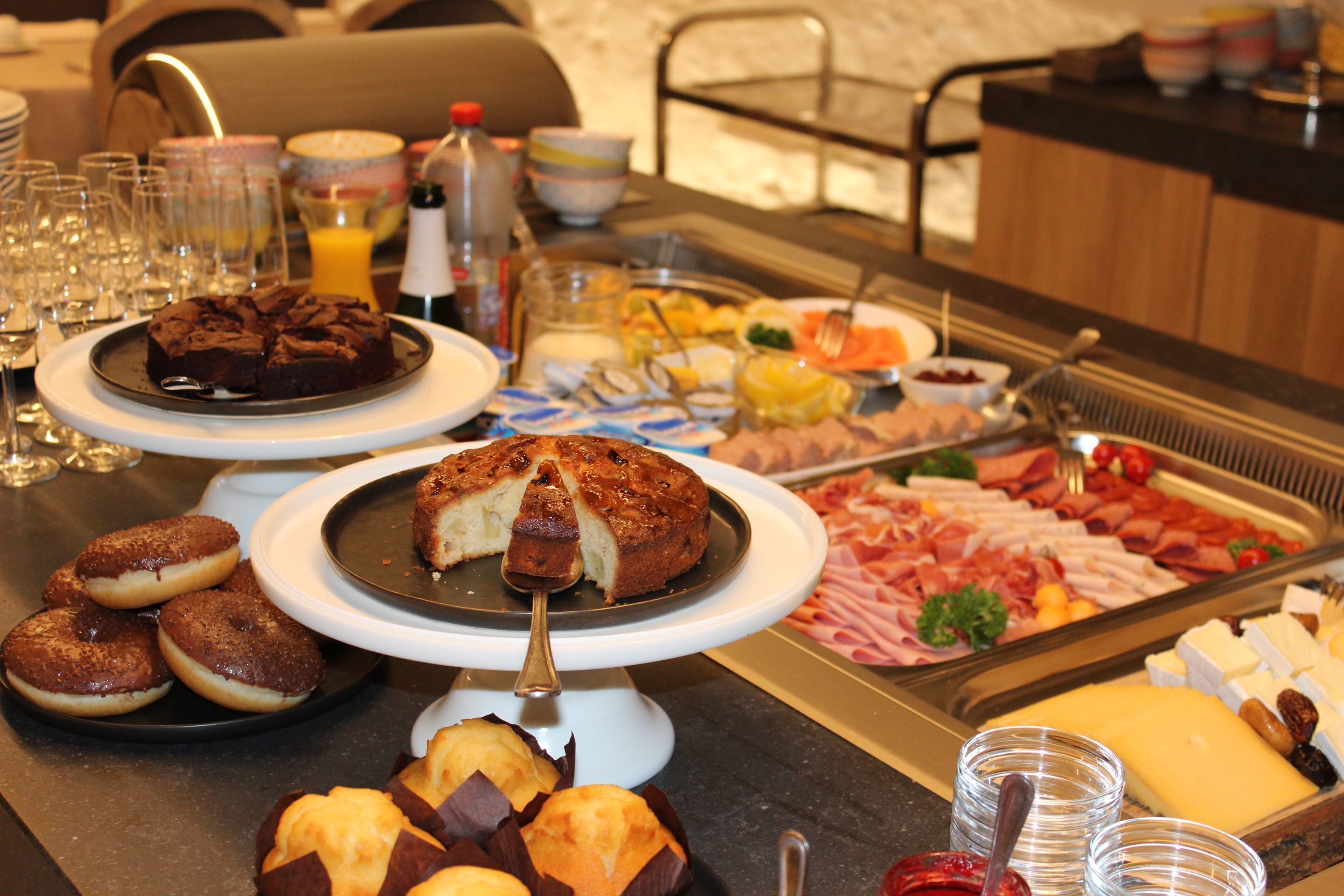 Une table de buffet proposant une variété de plats, notamment des pâtisseries, des viandes et des fromages.
