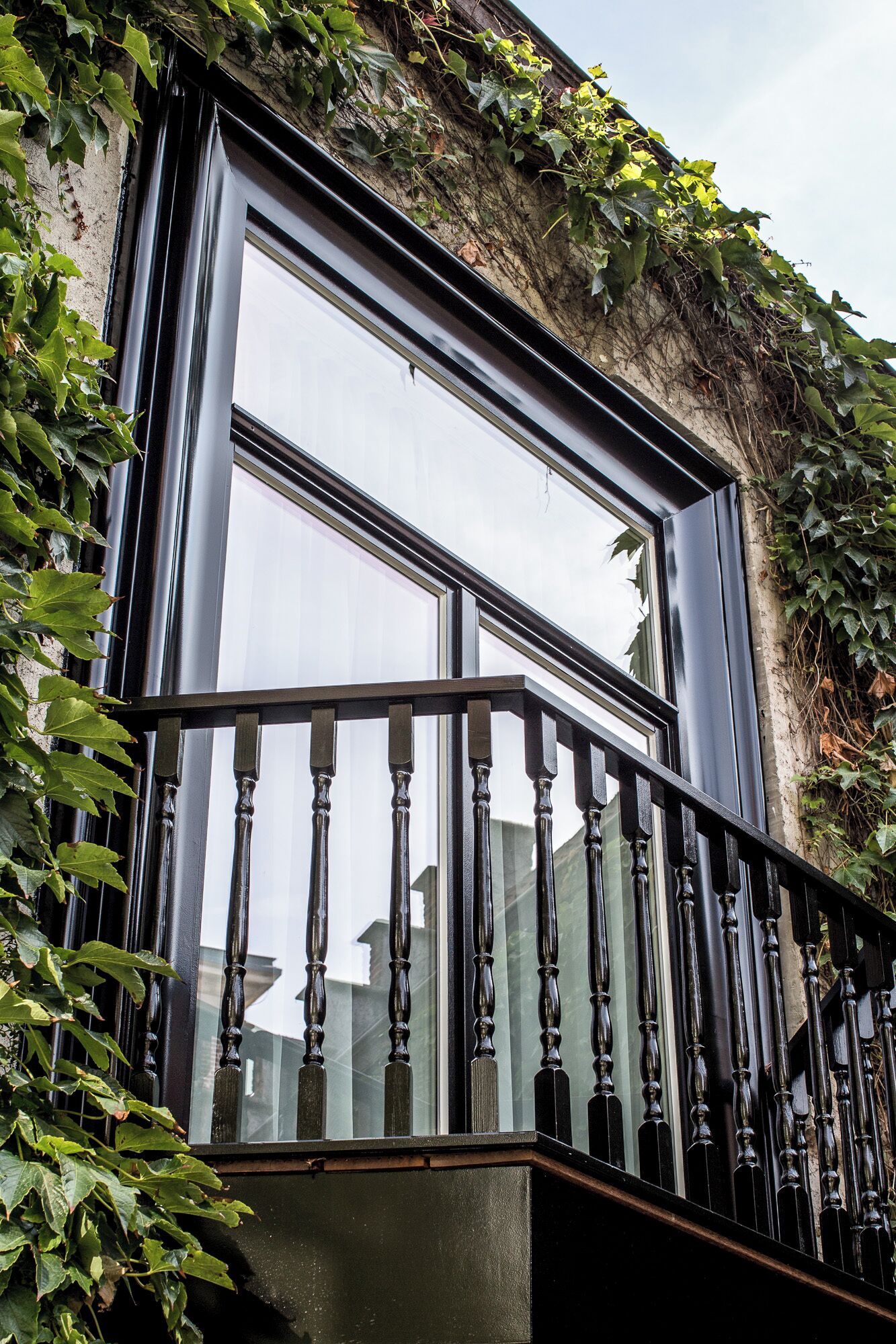 Una ventana con marco de metal negro y barandilla de madera.