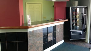 A kitchen with a marble countertop, a refrigerator stocked with snacks, and a door in the background.