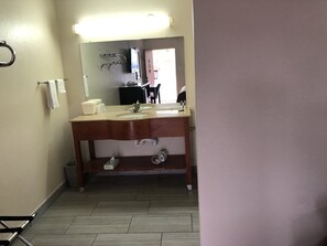 A bathroom with a wooden vanity, two sinks, a mirror, and a towel rack.
