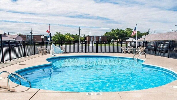 A round swimming pool with a metal ladder, surrounded by a black fence. - Castle Inn & Suites (Niagara Falls)