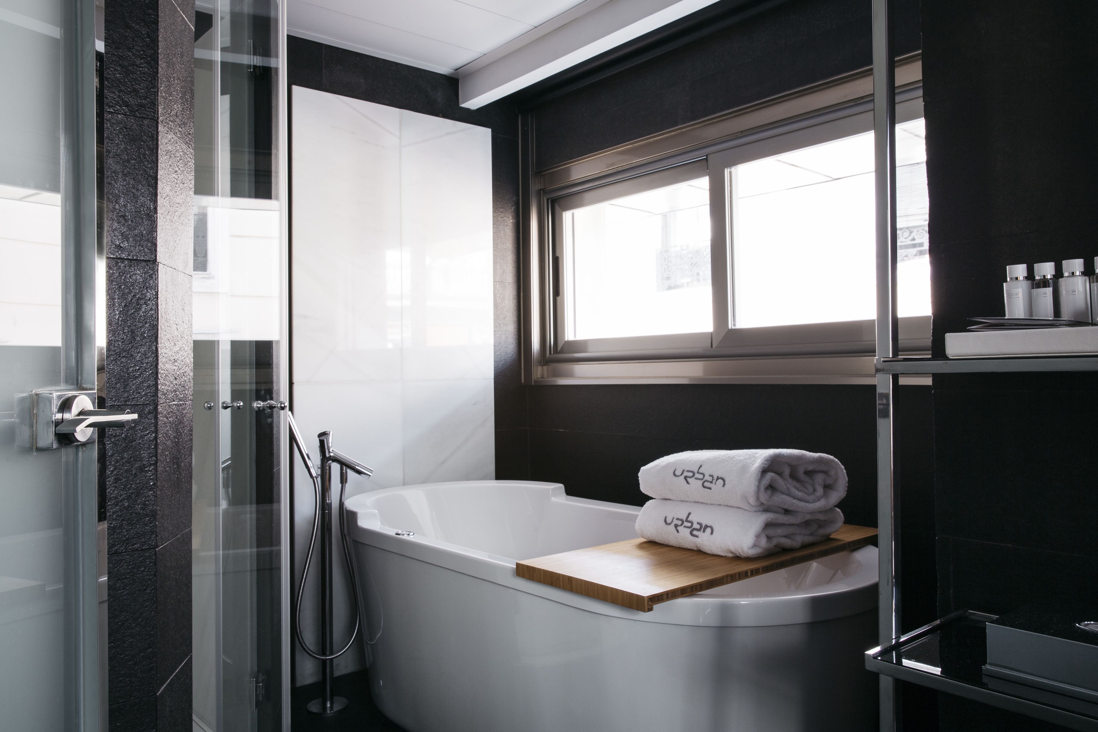 Un baño moderno con bañera, cabina de ducha de vidrio y ventana que proporciona luz natural.