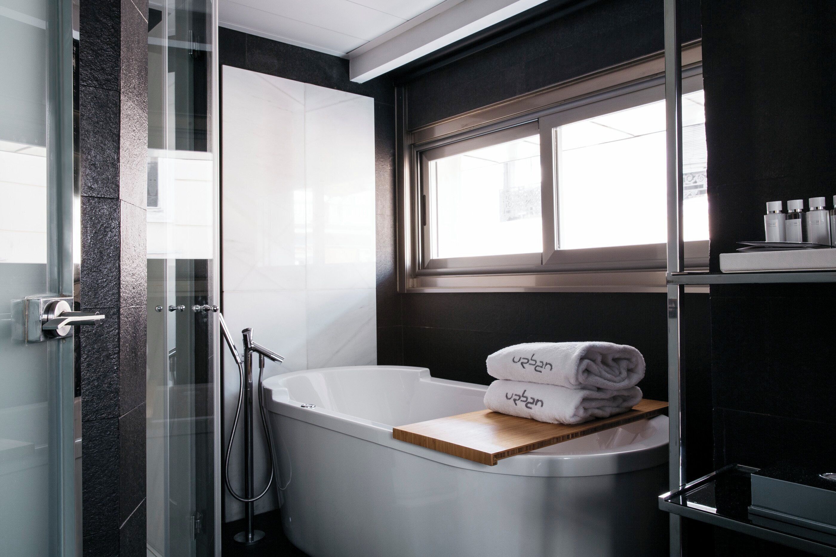 A modern bathroom with a freestanding bathtub, a glass shower enclosure, and a window providing natural light.