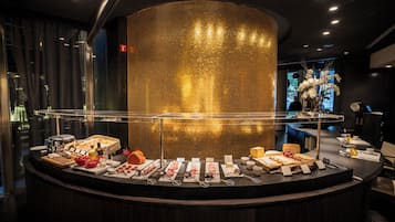 Balcão de buffet com diversos alimentos e utensílios, uma estrutura dourada decorativa em tela e design de interiores moderno.