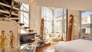 A modern hotel room with a large bed, a glass desk with a computer, a TV, and a staircase with a view to the outside. - Hotel Urban, a Small Luxury Hotel of the World  (Madrid)