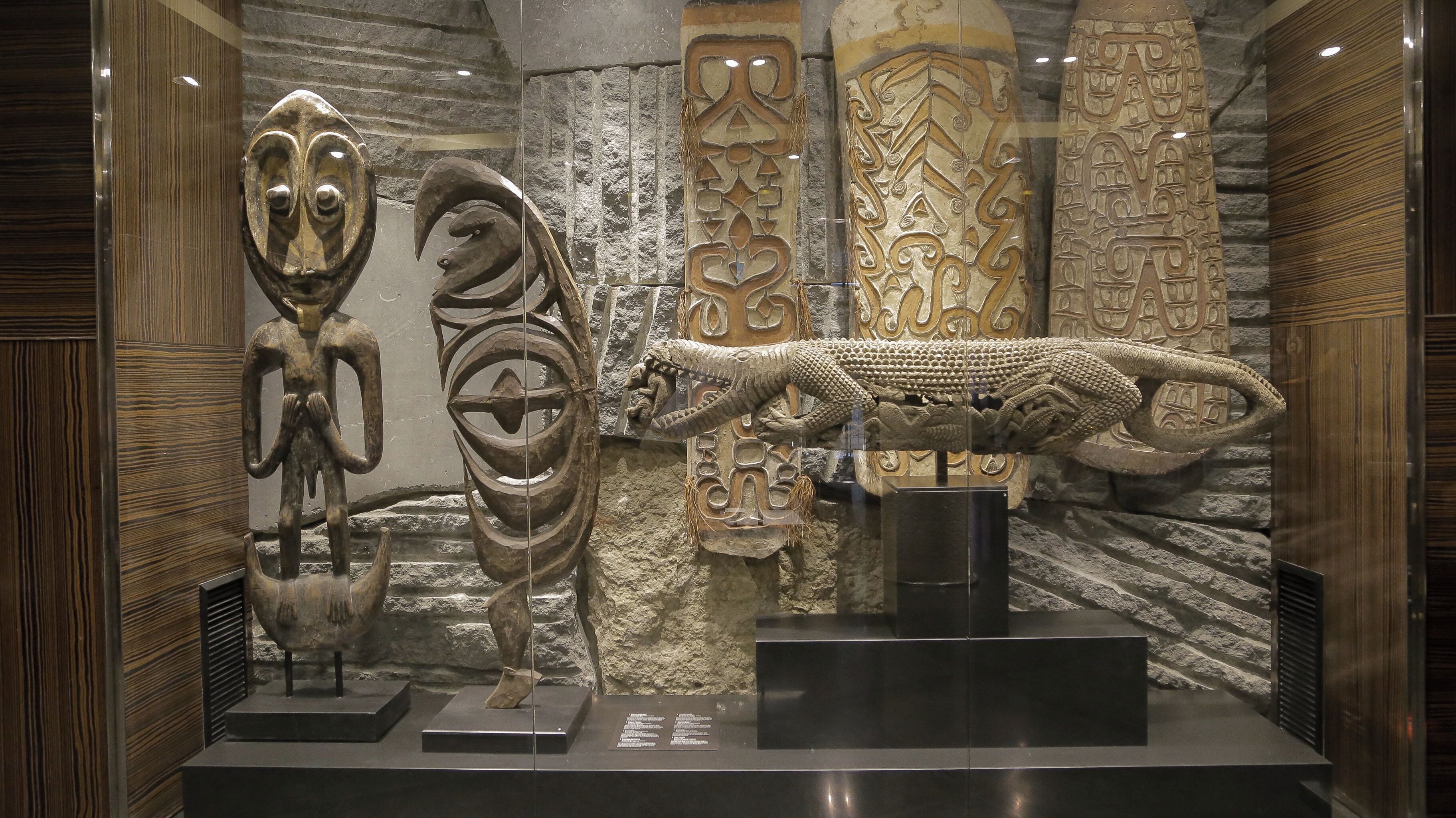 Une exposition d’artefacts anciens comprenant une grande sculpture, une statuette anthropomorphe plus petite et une sculpture de serpent très détaillée.
