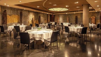 A spacious dining area with round tables, black chairs, and a modern ceiling design.
