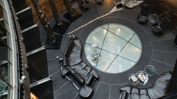 A modern atrium with a central glass table surrounded by seating, a spiral staircase, and a large sculpture. - Hotel Urban, a Small Luxury Hotel of the World  (Madrid)