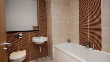 A modern bathroom with a toilet, sink, and bathtub.