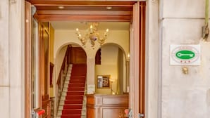 A hotel entrance with a red carpet, wooden interior, and a staircase leading inside. - Hotel Hesperia (Venice)