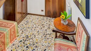 A spacious room with a high ceiling, a wooden staircase, a wooden door, a mosaic floor, and a table with a vase of flowers. - Hotel Hesperia (Venice)