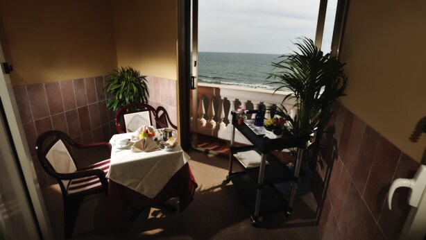 Un balcón con una mesa dispuesta para dos personas, con vistas al mar.