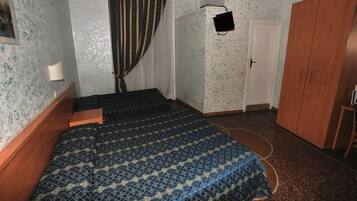 Un dormitorio con una cama, un armario de madera, una mesita de noche con una lámpara y una puerta.