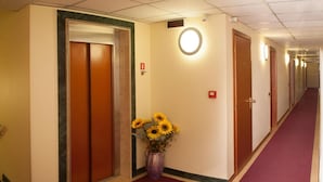 A hotel hallway with wooden doors, a marble border, and a red carpet.