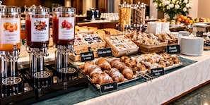 Un buffet proposant une variété de plats, notamment des pâtisseries, du pain et des boissons.
