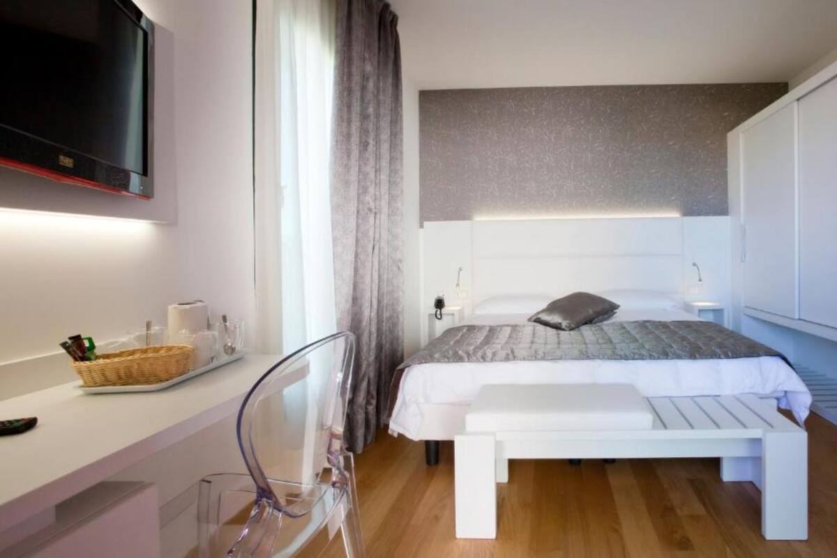 A modern bedroom with a bed, bedside table, and a TV mounted on the wall.