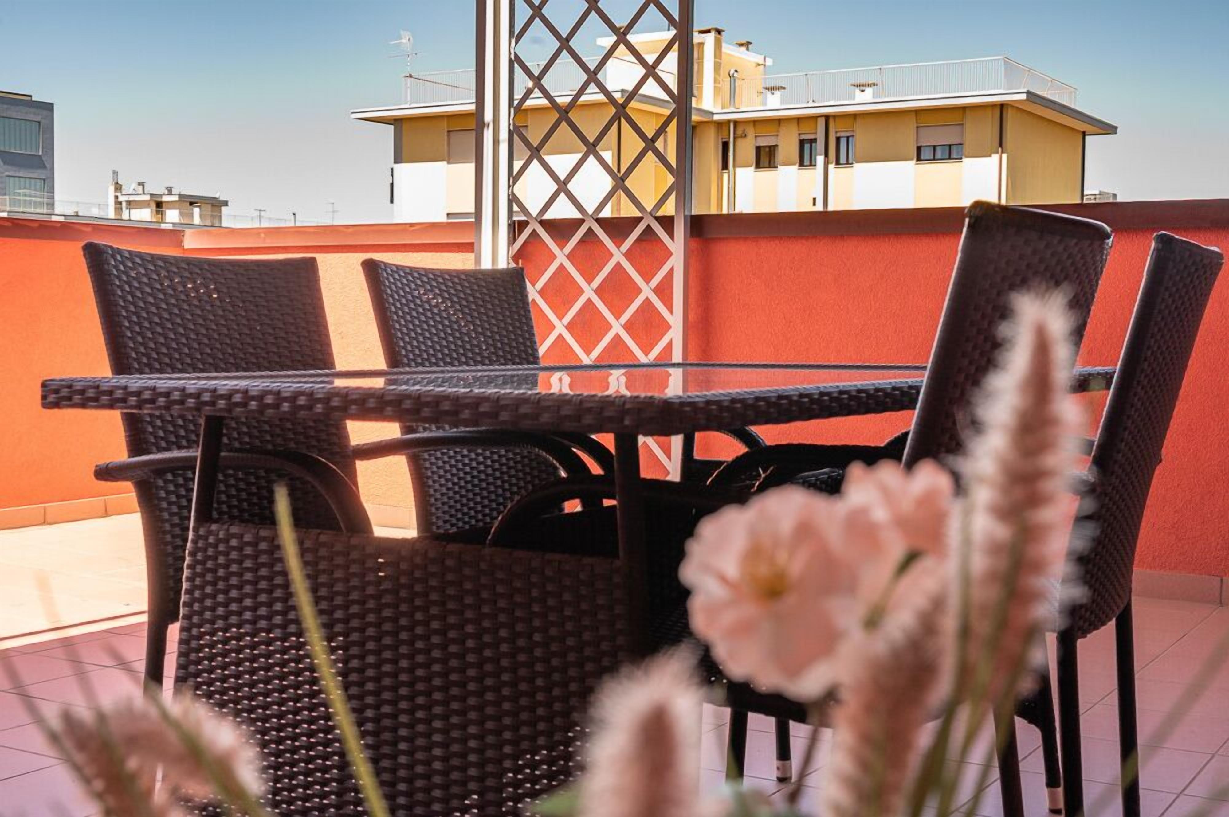 Una terraza con una mesa y sillas, un celosía divisoria y un edificio al fondo.