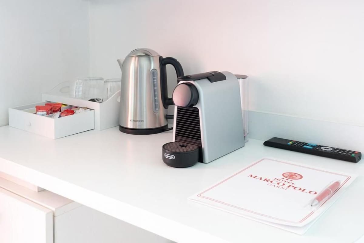 Una encimera de cocina con una tetera, una cafetera, un control remoto y una libreta.
