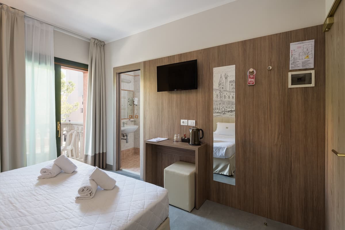 A hotel room with a bed, a desk, a television, and a mirror.