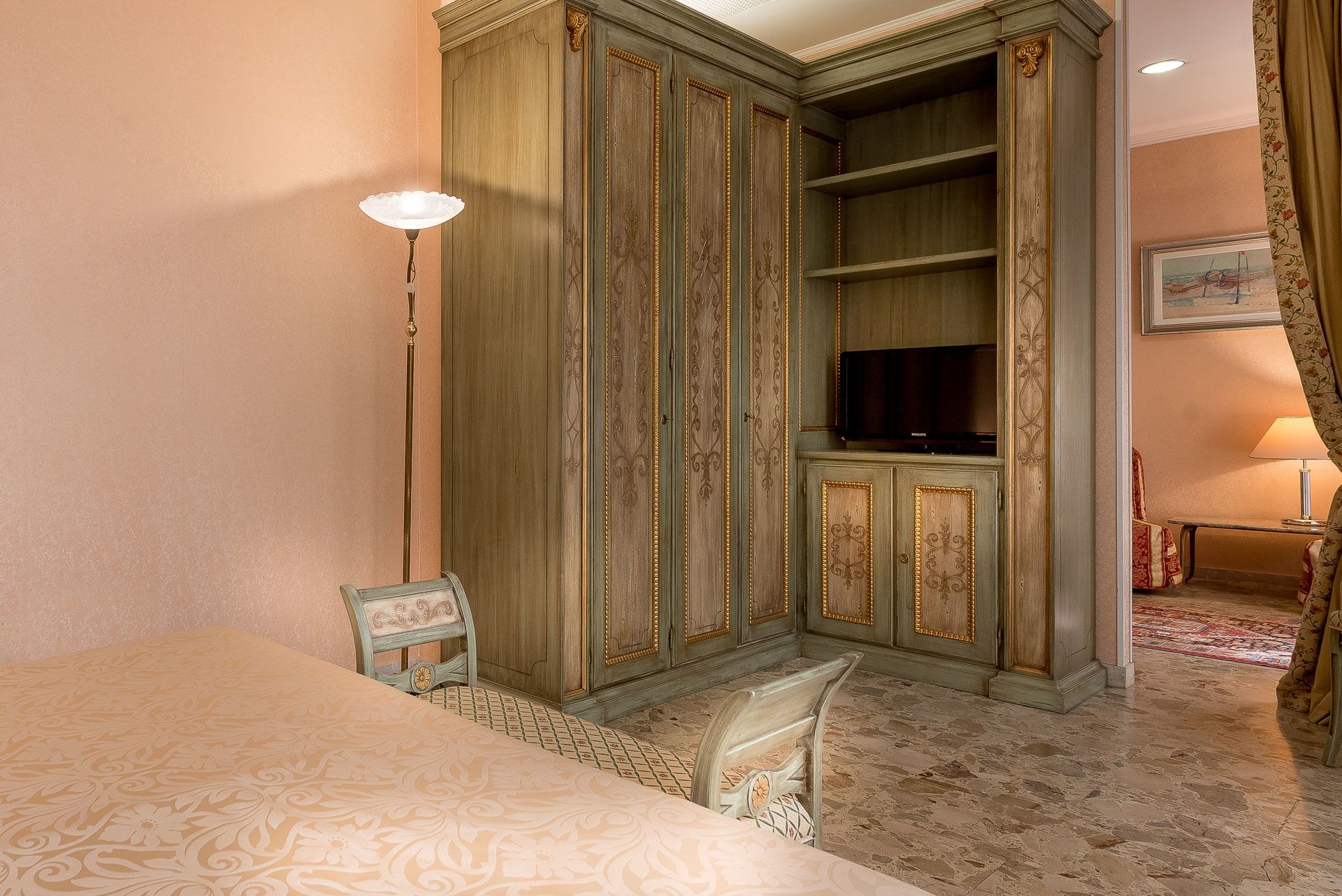 A hotel room with a bed, a television, a wardrobe, and a chair.