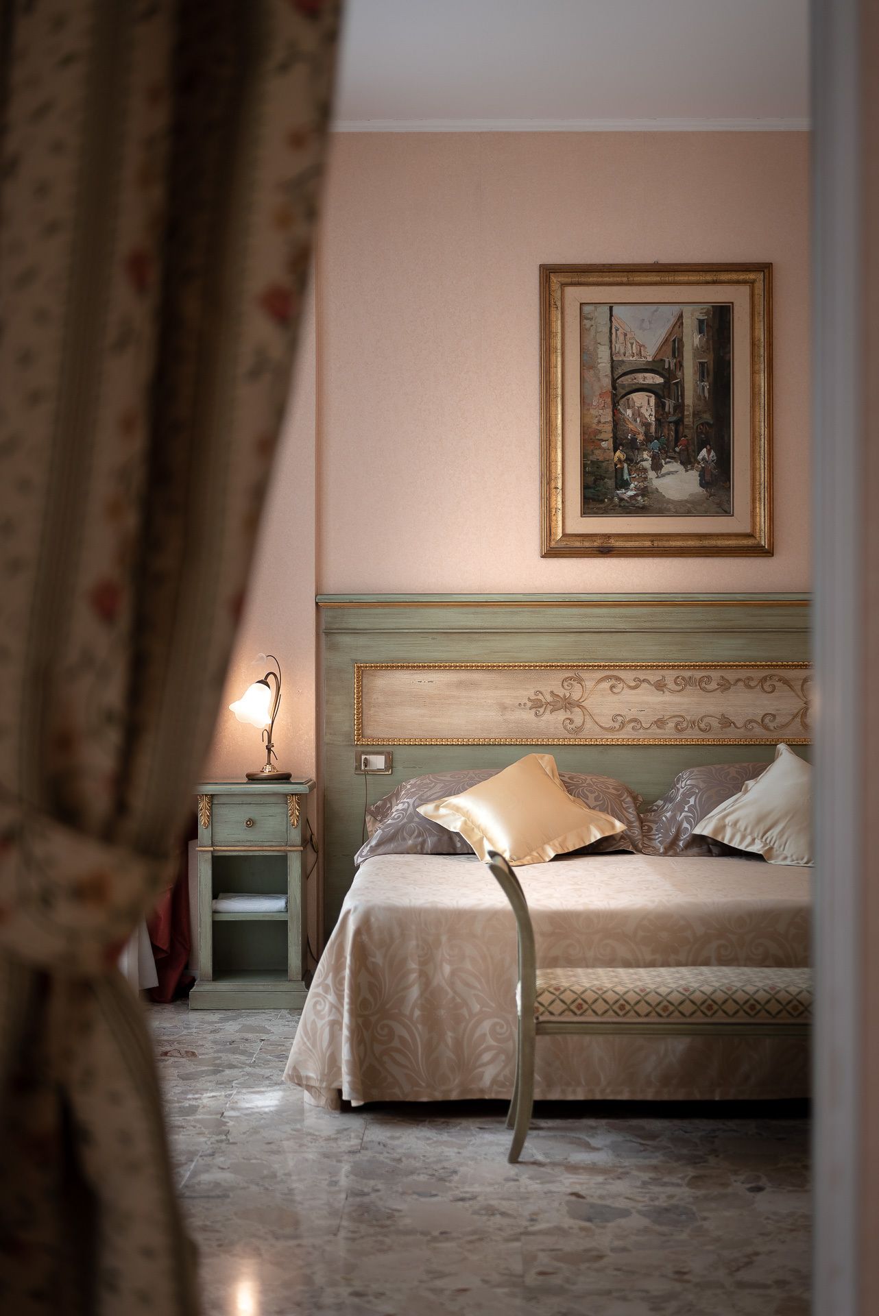 Un dormitorio con cama, una mesita de noche, una lámpara y un cuadro en la pared.