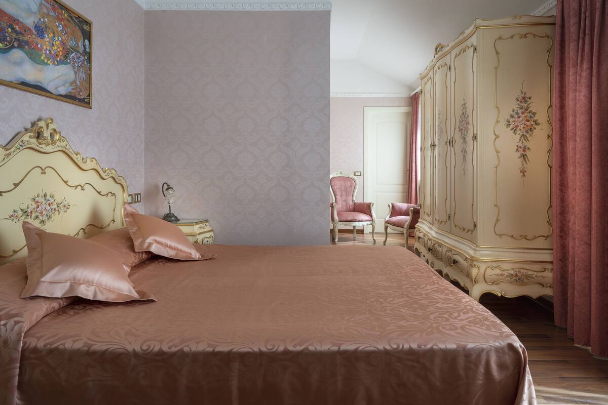 Ein Schlafzimmer mit einem großen Bett, einem Nachttisch, einem Sessel und einem Kleiderschrank.